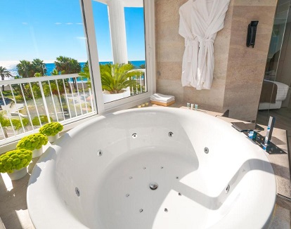 Foto de la bañera de hidromasaje circular con chorros de hidroterapia que se encuentra en el baño junto a un ventanal grande con vistas al mar