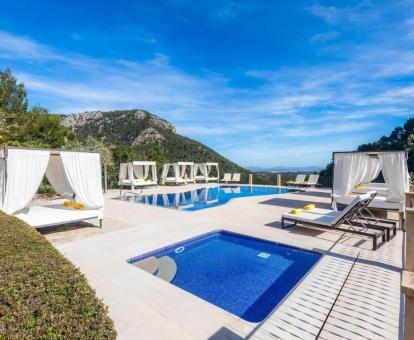Amplia zona exterior con piscinas y solarium con tumbonas y camas balinesas rodeada de vegetación de este coqueto hotel.