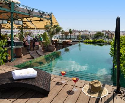 Preciosa piscina rodeada de vegetación y vistas a la ciudad en la terraza del hotel.