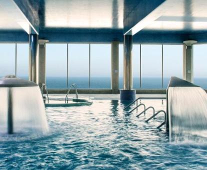 Gran piscina de hidroterapia con vistas al mar del centro de bienestar del hotel.