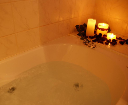 Foto de la bañera de hidromasaje con velas y pétalos de rosa que se encuentra en la Posada Rural Fontibre

