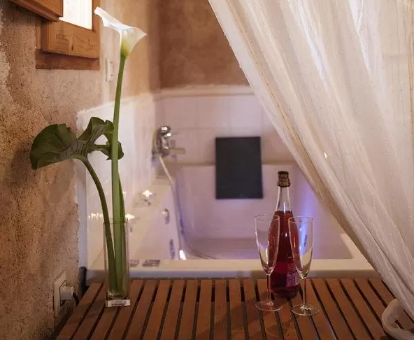 Foto de la bañera de hidromasje con una botella de vino y dos copas de la Casa Rural El Simarro