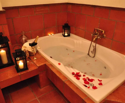 Foto de la bañera de hidromasahe con pétalos de rida y una botella de champán del Hotel Los Cerezos 