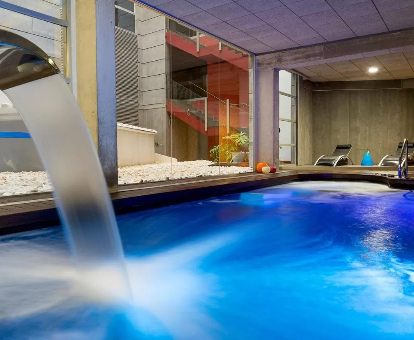 Foto de la piscina cubierta con cascada y tumbonas del spa que se encuentra en el Hotel Spa La Casa del Rector
