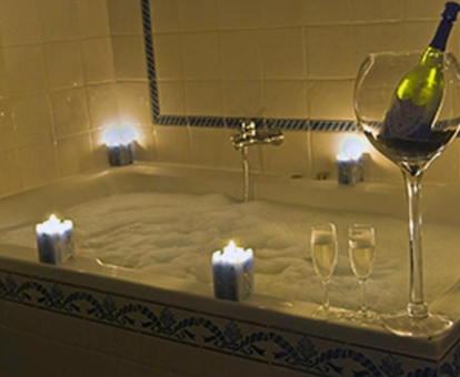 Foto de una bañera de hidromasaje con espuma, velas aromáticas y copas de champán en el hotel Los Bronces
