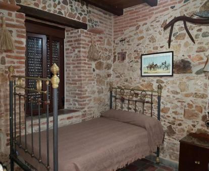 Hermosa habitación de estilo tradicional con paredes de piedra a la vista de esta casa rural independiente.