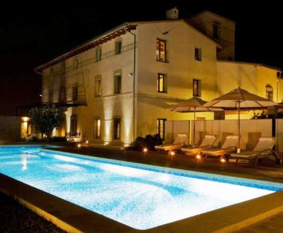 Edificio con una amplia piscina exterior e iluminación nocturna de este hotel con encanto.