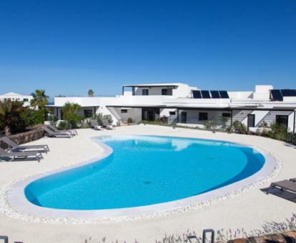 Coqueto hotel rural con piscina exterior y solarium con tumbonas.