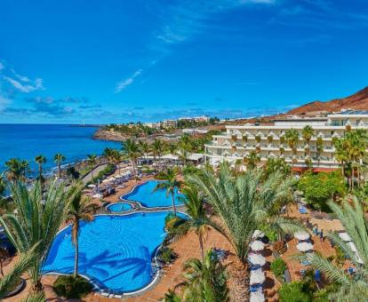 Vista aérea de este precioso hotel con amplia piscina rodeada de palmeras y cerca del mar.